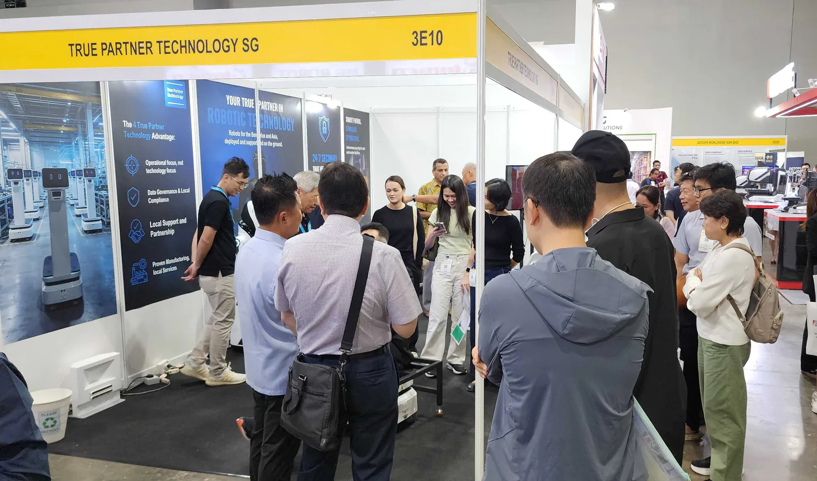 Visitors gathered at the True Partner Technology stand, in front of the panels setting out the four advantages.